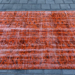 May include: A vintage-style rug with a faded orange and black pattern. The rug has a distressed look and is made of a soft, woven material.
