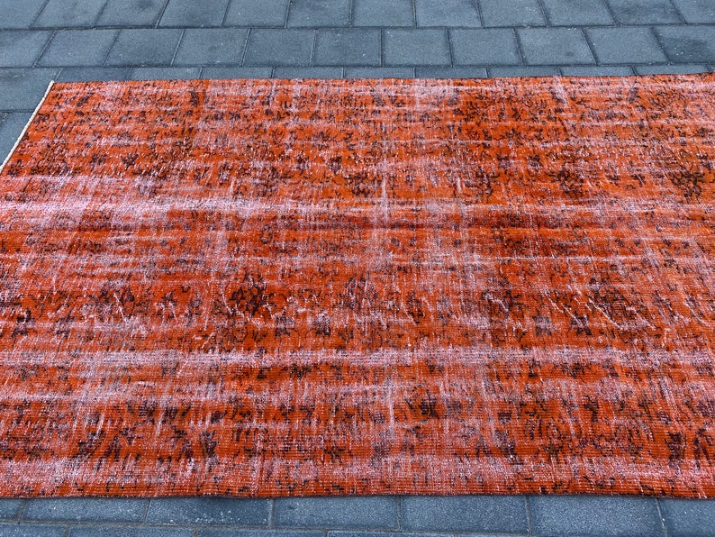 May include: A vintage-style rug with a faded orange and black pattern. The rug has a distressed look and is made of a soft, woven material.