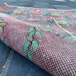 May include: A close-up of a pink and white woven rug with a floral pattern. The rug is rolled up and the floral pattern is visible on the outside of the roll.