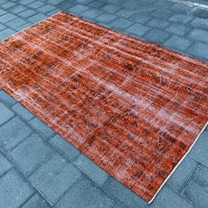May include: A vintage-style rug with a faded orange and black pattern. The rug has a distressed look and is made of a soft, woven material.