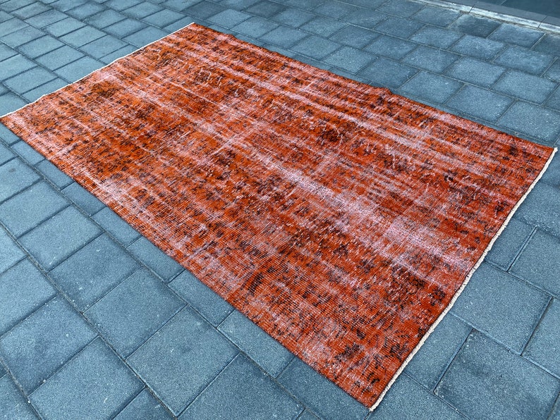 May include: A vintage-style rug with a faded orange and black pattern. The rug has a distressed look and is made of a soft, woven material.