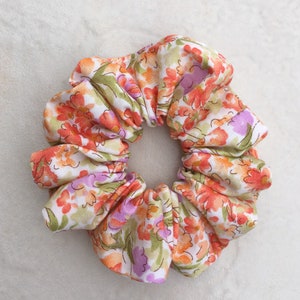 May include: A white, orange, and purple floral print scrunchie.