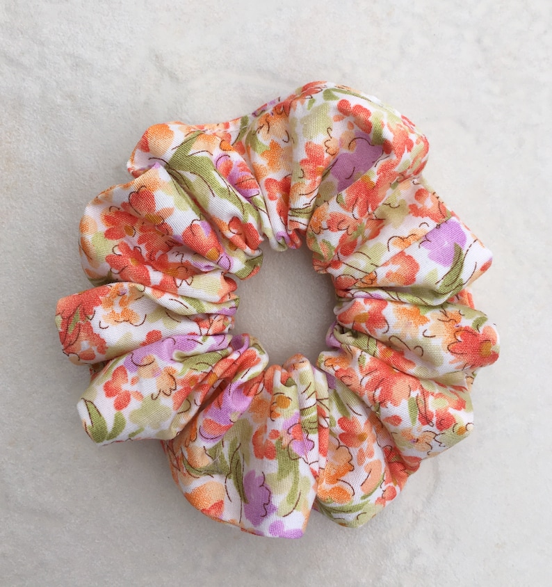 May include: A white, orange, and purple floral print scrunchie.
