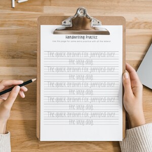 May include: A handwriting practice worksheet with the phrase "The quick brown fox jumped over the lazy dog." repeated on lined paper. The worksheet is on a clipboard with a black pencil on top.