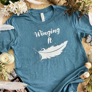 Winging It Unisex T-Shirt | Angels of Elysium Olivia Wildenstein | OFFICIALLY LICENSED | Feather | Celestial | Starlight