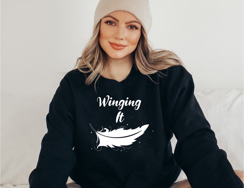 May include: Black sweatshirt with white text that reads "Winging It" and a white feather graphic.