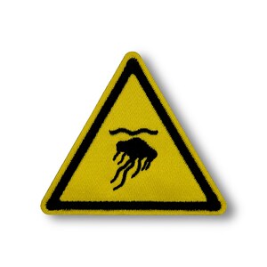May include: Yellow triangle warning sign with a black border. The sign has a black image of a jellyfish in the water.