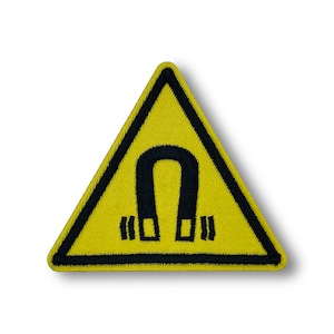 May include: Yellow triangle warning sign with a black outline and a black horseshoe magnet inside. The magnet has two black lines on each side.