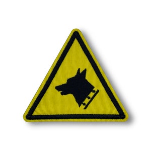 May include: Yellow triangle warning sign with a black silhouette of a dog's head inside. The dog is wearing a collar with spikes.