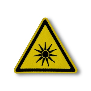 Può includere: Segnale di avvertimento triangolare giallo con bordo nero e un simbolo di raggio laser nero all'interno.