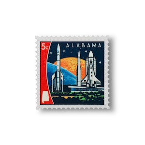 May include: A vintage postage stamp depicting three spacecraft against a sunset and starry sky. The stamp is labelled "ALABAMA" and has a red border with the state outline. The stamp is 5 cents.