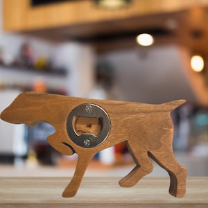 May include: Wooden dog-shaped bottle opener with a metal bottle opener in the center. The bottle opener is brown and has a natural wood finish.