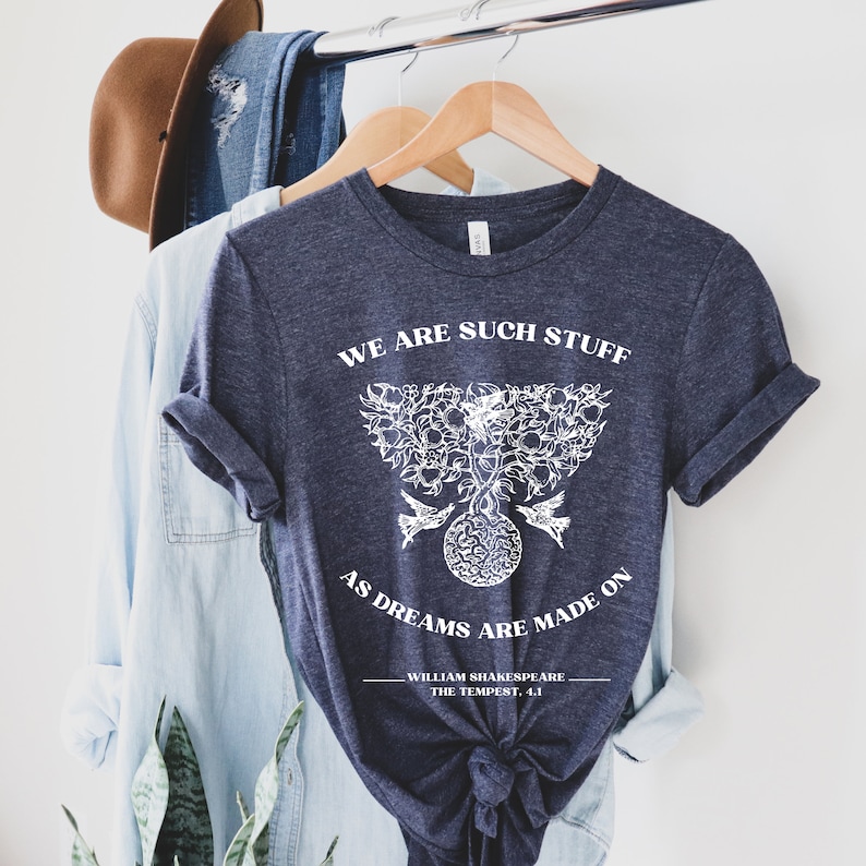 May include: A dark blue t-shirt with a white graphic design featuring a tree with birds and the text "We are such stuff as dreams are made on - William Shakespeare, The Tempest, 4.1".