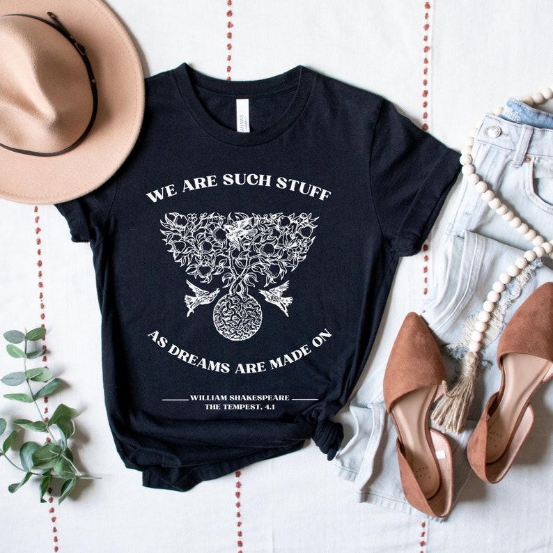 May include: Black t-shirt with a white graphic of a tree with birds and a quote from William Shakespeare's The Tempest: "We are such stuff as dreams are made on."