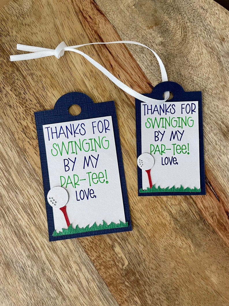 May include: Two blue and white gift tags with a golf ball and tee design. The text on the tags reads "Thanks for swinging by my par-tee! Love."
