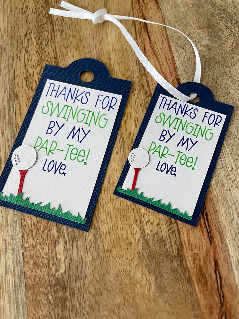 May include: Two blue and white gift tags with a golf ball and tee design. The text on the tags reads "Thanks for swinging by my par-tee! Love."