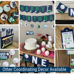 Puede incluir: Decoraciones para una fiesta de primer cumplea&ntilde;os con tem&aacute;tica de golf, que incluyen una pancarta que dice "Feliz cumplea&ntilde;os", un adorno para pastel que dice "uno", adornos para cupcakes con forma de pelota de golf y un letrero que dice "&iexcl;Gracias por venir a mi par-tee! Con cari&ntilde;o."