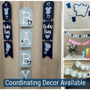 Op de afbeelding: Blauwe en witte babyborstdecoraties met de woorden "Baby Boy" en "Baby" op banners en vlaggetjes. De decoraties hangen aan een muur en bevatten een banner met de tekst "Baby Boy" en een banner met de tekst "Baby".