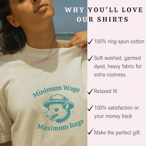 May include: A white t-shirt with a teal graphic of a possum wearing a hat and the text "Minimum Wage Maximum Rage". The shirt is advertised with a list of reasons why you'll love it, including 100% ring-spun cotton, soft washed fabric, relaxed fit, 100% satisfaction guarantee, and the fact that it makes a perfect gift.
