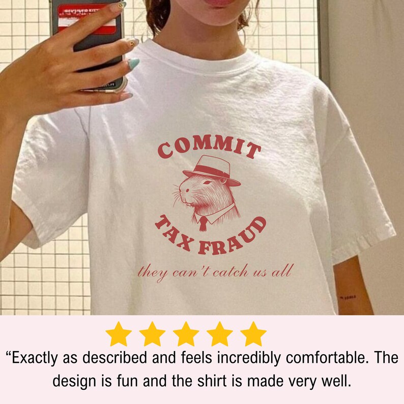 May include: White t-shirt with a red graphic of a capybara wearing a hat and tie. The graphic says "Commit Tax Fraud" and "they can't catch us all".