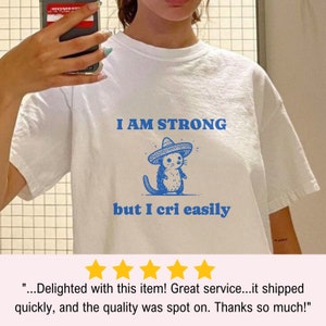 May include: White t-shirt with a blue cartoon mouse wearing a sombrero and the text "I AM STRONG but I cri easily".