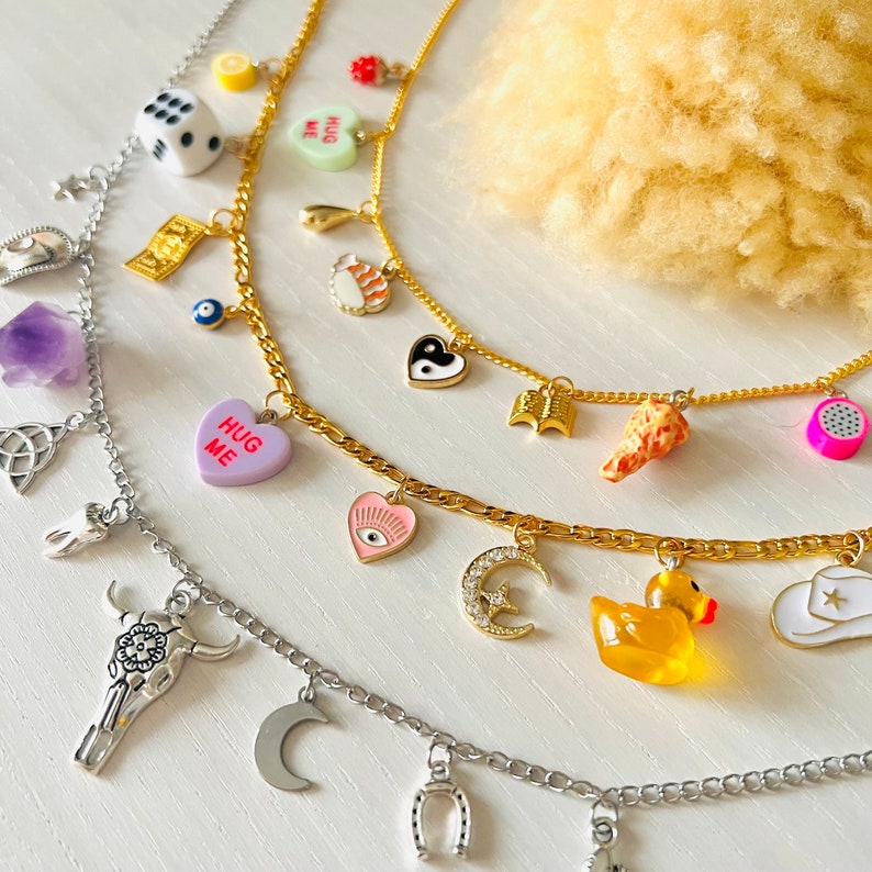 3 necklaces with various cute charms including a rubber ducky, moon, sushi, cowboy hat, book, dragon fruit and 3d chicken wing