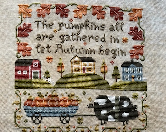 Let Autumn Begin, pig pulling wagon full of pumpkins, houses and barn on hills primitive folk art cross stitch pattern by Acadia Stitchery
