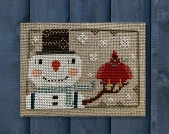 Frosty e seu amigo, um adorável boneco de neve em estilo vintage, com chapéu preto, cachecol e cardeal, em um padrão de ponto cruz primitivo de arte folclórica em PDF da Acadia Stitchery.