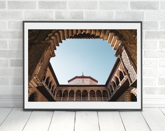 May include: A view of a courtyard with a blue sky visible through a series of arches. The arches are made of stone and have intricate carvings. The courtyard is surrounded by buildings with balconies.