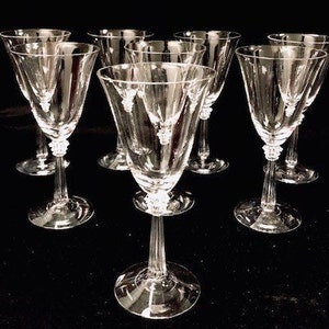 May include: Set of eight clear glass wine glasses with a fluted design. The glasses have a tall, slender stem and a round bowl.