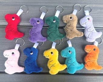 May include: A collection of ten plush dinosaur keychains in various colors, including red, purple, green, tan, light purple, pink, blue, yellow, teal, and orange. Each keychain features a silver ring and a white fabric loop.