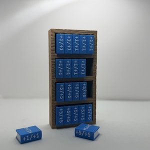 May include: A miniature wooden bookshelf filled with blue books. Each book has white text, with the text "+1/+1" or "+5/+5". Two books are separate from the bookshelf. The bookshelf is brown and has a textured appearance.
