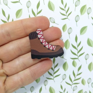 Könnte beinhalten: Ein brauner Wanderschuh mit roten Schnürsenkeln und einem weißen Besatz. Der Schuh ist aus Leder und hat eine Gummisohle.