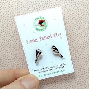 May include: A pair of wooden earrings featuring a long-tailed tit bird design. The earrings are made in the UK using sustainable, responsibly sourced wood. The text "THE ZEN WOODPECKER" and "Long Tailed Tits" is printed on the card.