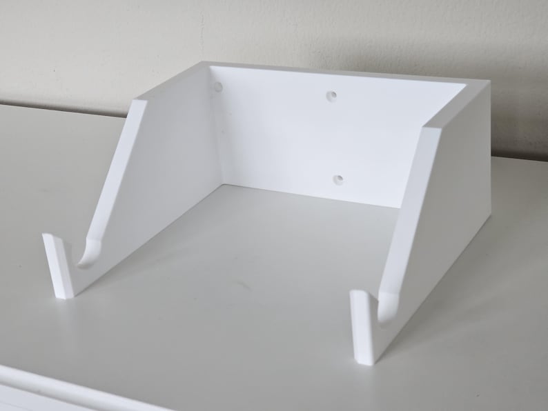 May include: White wall-mounted shelf with two hooks, designed to hold a guitar or other items.