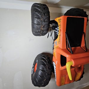May include: Orange and black toy monster truck with large wheels and the text "El Loco" on the side.