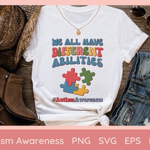 以下が含まれることがあります： レトロなスタイルのカラフルな文字で「WE ALL HAVE DIFFERENT ABILITIES」と書かれた白いTシャツ。テキストの下には、赤、青、緑、黄色の4つのパズルのピースがあります。ハッシュタグ#AutismAwarenessが一番下にあります。