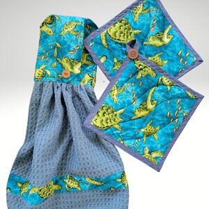 Op de afbeelding: Een set van drie keukendoeken met een blauw en groen zeeschildpad ontwerp. De doeken zijn gemaakt van wafelweefsel en hebben een blauwe en groene rand. De doeken zijn perfect om een ​​toets van whimsy aan uw keuken toe te voegen.