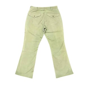 Op de afbeelding: Een lichtgroene cargo broek met twee achterzakken en een knoopsluiting.