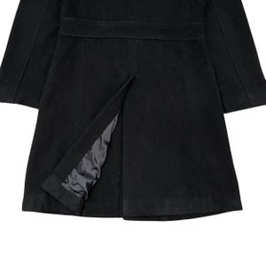 May include: A black coat with a tailored design. The coat features a notched collar, a belt detail at the waist, and a split at the hem. The interior lining is visible through the split.