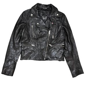 May include: Black leather motorcycle jacket with a classic asymmetrical zipper closure. The jacket features multiple zippered pockets, a notched collar, and silver hardware. The leather has a textured, slightly distressed appearance, giving it a vintage look. The jacket is a stylish outerwear piece.