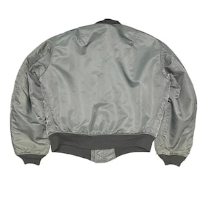 Puede incluir: Chaqueta bomber verde salvia con cuello, pu&ntilde;os y cintura negros. La chaqueta est&aacute; hecha de un material liso, posiblemente nailon o poli&eacute;ster, con un ligero brillo. El dise&ntilde;o es de estilo bomber cl&aacute;sico, con dobladillo y pu&ntilde;os acanalados.