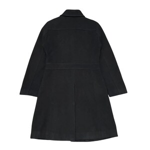 May include: A black coat with a collar, two front pockets, and a belt detail at the waist. The coat has long sleeves and a knee-length hem. The back of the coat is visible in the image.