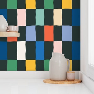 May include: A kitchen with a black and white checkered wallpaper with colorful squares. The wallpaper has green, blue, yellow, orange, pink, and white squares. There is a white pitcher and a small white jar on a wooden surface.