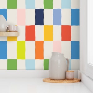 Peut inclure: Un mur blanc avec un papier peint à motif de carreaux colorés. Le papier peint présente des carrés de vert, bleu, rose, orange, jaune et rouge. Un pichet blanc et un petit pot blanc sont posés sur un dessous-de-verre en bois dans le coin de la pièce.