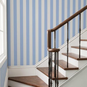 May include: A staircase with wooden steps and a dark brown handrail. The wall is painted with vertical stripes in light blue and white. A window is visible on the left side of the image.