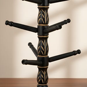 May include: A black wooden mug tree with a decorative base and multiple arms extending outwards. The tree features gold-colored leaf-like accents and is designed to hold mugs. The overall design is rustic and decorative.