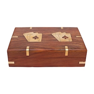 May include: A rectangular wooden box with a dark brown finish. The box is adorned with brass accents and features inlaid brass playing card designs on the lid. The playing card designs are of the Ace of Spades.
