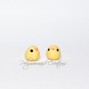 May include: Two yellow chick-shaped polymer clay creations with black eyes and small pink beaks. The creations are on a white background. The text "Polymermermaid Creations" is written in cursive below the creations.
