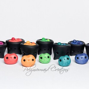 May include: A set of 10 miniature black cauldrons with colorful bubbling potions and matching jelly bean charms. The cauldrons have cute faces and are arranged in a rainbow color order.